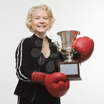 Royalty Free Photo of a Senior Woman Wearing Boxing Gloves Holding a Trophy