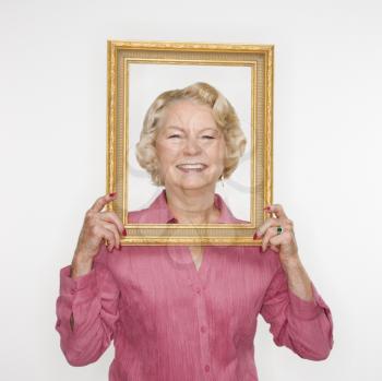 Royalty Free Photo of an Older Woman Holding a Picture Frame Over Her Face