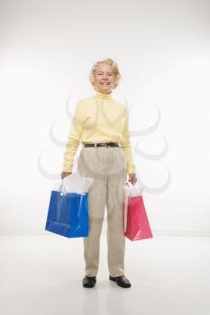Royalty Free Photo of an Older Woman Holding Gift Bags and Smiling