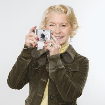 Caucasian senior woman taking photo with digital camera of viewer.