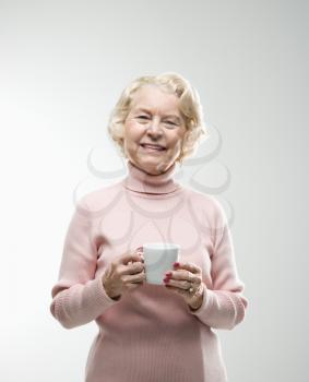 Royalty Free Photo of a Senior Woman Holding a Coffee Cup and Smiling