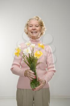 Caucasian senior woman holding bouquet and smiling at viewer.