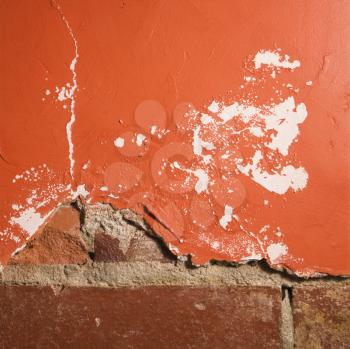 Royalty Free Photo of a Red Wall With Cracking Plaster and Brick