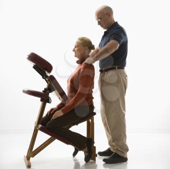 Royalty Free Photo of a Massage Therapist Massaging the Back of a Woman Sitting in a Massage Chair 