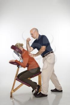Royalty Free Photo of a Massage Therapist Massaging the Back of a Woman Sitting in a Massage Chair