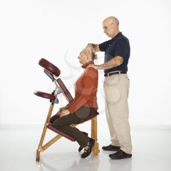 Royalty Free Photo of a Massage Therapist Massaging the Neck of a Woman Sitting in a Massage Chair.
