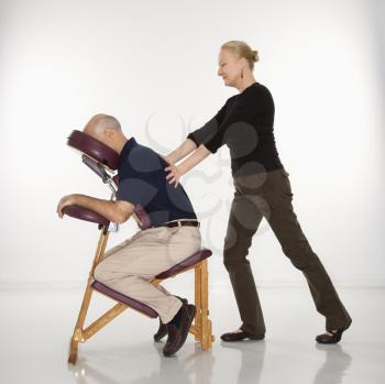 Royalty Free Photo of a Female Massage Therapist Massaging the Back of a Man Sitting in a Massage Chair