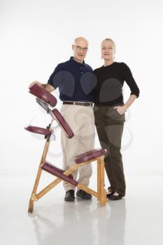 Royalty Free Photo of Male and Female Massage Therapists Standing Beside a Massage Chair