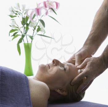 Royalty Free Photo of a Caucasian Male Massage Therapist Massaging the Temples of a Caucasian Woman Lying on Massage Table