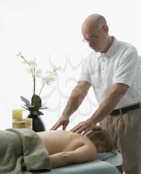 Royalty Free Photo of a Male Massage Therapist Massaging the Back of a Woman Lying on a Massage Table