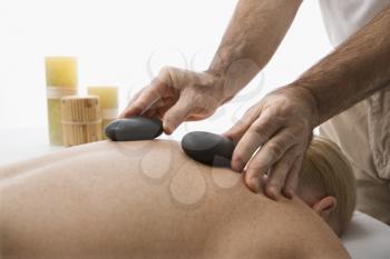 Royalty Free Photo of a Massage Therapist Placing Hot Stones on a Woman' Back