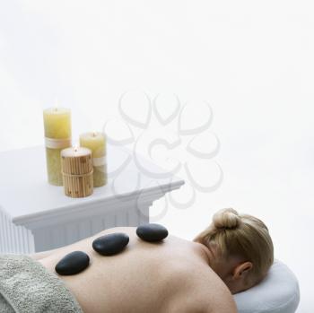 Royalty Free Photo of a Middle-aged Woman Lying on a Massage Table with Hot Stones on Her Back