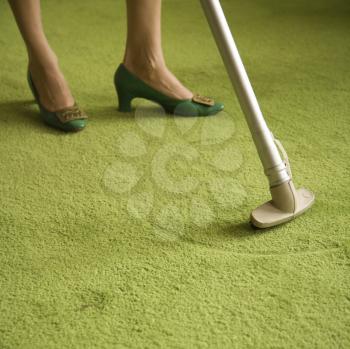 Royalty Free Photo of a Close-Up of a Woman's Feet With a Vacuum Extension Against a Green Retro Carpet