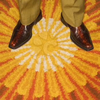 Royalty Free Photo of a Close-up of Male Feet in Vintage Shoes Against a Sunburst Rug