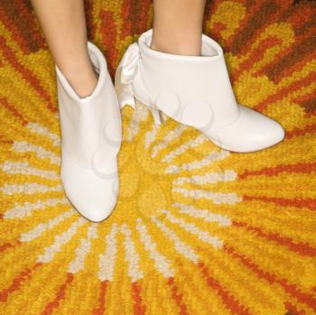 Royalty Free Photo of Female Feet in White Vintage Boots Against a Sunburst Rug