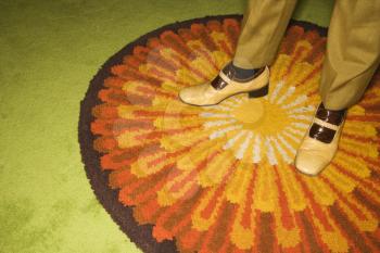 Royalty Free Photo of a Close-up of Male Feet in Vintage Shoes Against a Sunburst Rug