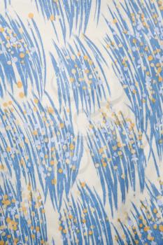 Close-up of vintage fabric with abstract blue and yellow brushstrokes printed on polyester.