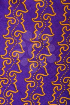 Royalty Free Photo of a Close-up of Purple Vintage Fabric With Repetitive Orange Designs Printed on Polyester