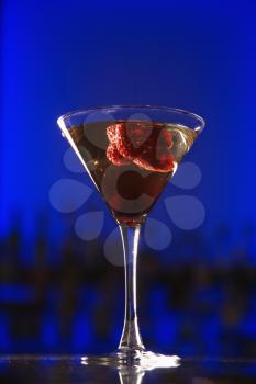 Royalty Free Photo of a Martini Cocktail With Raspberry Fruit Against a Glowing Blue Background