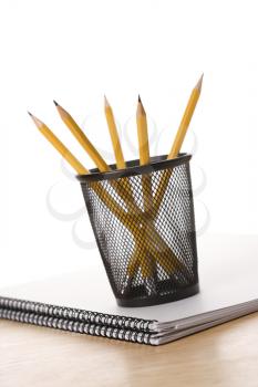 Pencils in pencil holder on top of spiral bound notebook.