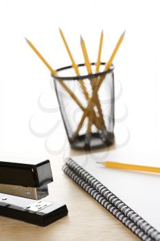 Pencils, a stapler, and spiral bound notebooks arranged on a desk.