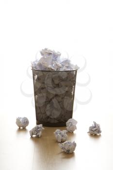Royalty Free Photo of a Selective Focus of a Wire Mesh Trash Can With Crumpled Paper Scattered Around