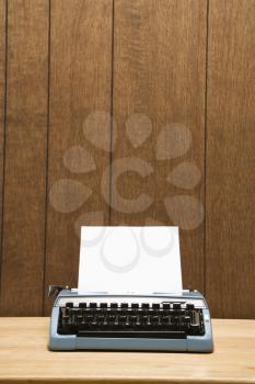 Royalty Free Photo of a Vintage Blue Typewriter on a Desk With Wood Paneling