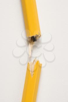 Wooden yellow pencil broken with lead exposed against white background.