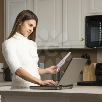 Royalty Free Photo of a Woman Typing on a Laptop in Her Kitchen