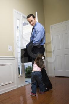 Royalty Free Photo of a Businessman at an Opened Door With His Daughter Tugging on His Leg