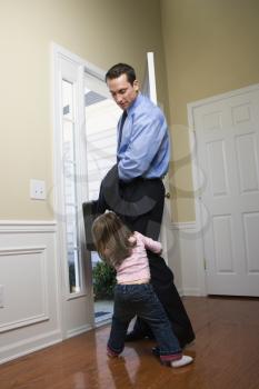 Royalty Free Photo of a Businessman at an Opened Door With His Daughter Tugging on His Leg