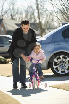 Royalty Free Photo of a Father Helping His Daughter Ride a Bicycle