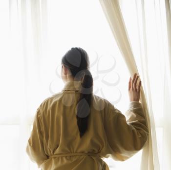 Royalty Free Photo of a Woman in a Bathrobe Looking Out the Window