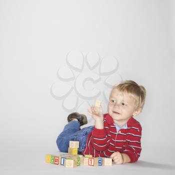 Royalty Free Photo of a Toddler Boy Laying Playing With Toys