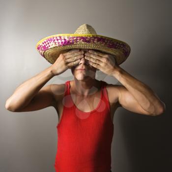 Royalty Free Photo of a Man Wearing a Sombrero and Covering His Eyes