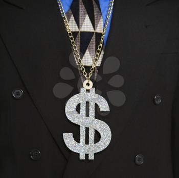 Man in suit wearing necklace with money sign.