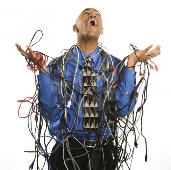 African American businessman wrapped in computer cables looking up with exasperation.