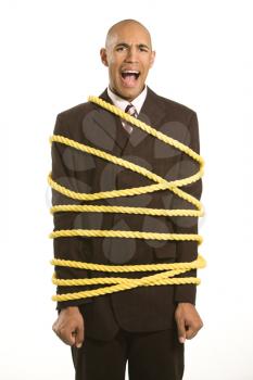 Royalty Free Photo of a Businessman Wrapped in Yellow Rope Screaming