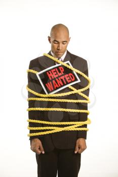 Royalty Free Photo of a Businessman Wrapped in Yellow Rope Wearing a Help Wanted Sign