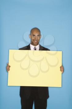 Royalty Free Photo of a Man Holding a Blank Sign Against a Blue Background