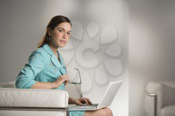 Royalty Free Photo of a Professional Businesswoman Sitting in an Office Working on a Laptop Computer 