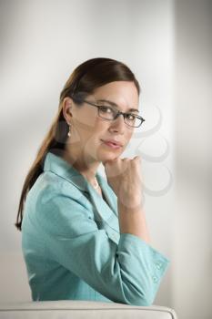 Caucasian mid adult professional business woman sitting in modern office looking at viewer slightly smiling.