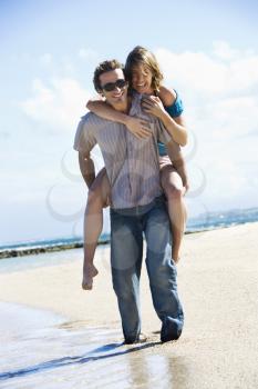 Royalty Free Photo of a Man Giving a Woman a Piggyback Ride on the Beach