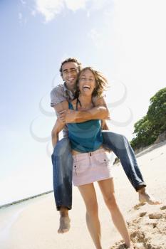 Royalty Free Photo of a Woman Giving a Man a Piggyback Ride on a Beach