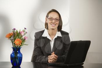 Royalty Free Photo of a Businesswoman Sitting at a Desk Smiling With Laptop Computer