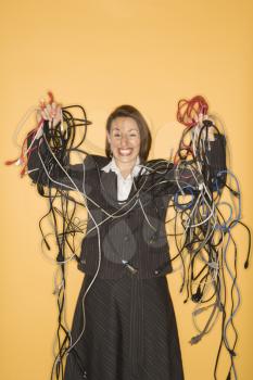Royalty Free Photo of a Businesswoman Smiling Holding a Pile of Tangled Cords and Wires