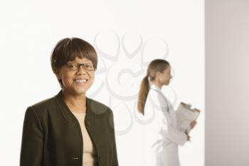 Royalty Free Photo of a Middle-aged Female Patient Smiling With a Doctor Standing in the Background