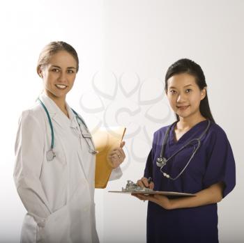 Royalty Free Photo of a Female Doctor Female Physician's Assistant Standing Together Smiling