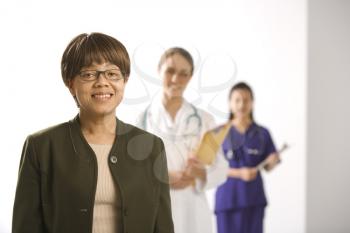 Royalty Free Photo of a Middle-aged Woman Smiling and With a Doctor and Her Assistant Standing in the Background