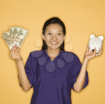 Royalty Free Photo of a Doctor Holding a Piggy Bank and Money